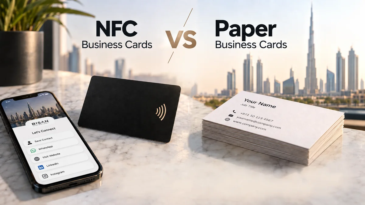An NFC business card and a stack of paper business cards on a marble table, with a phone showing a digital profile and the Dubai skyline behind