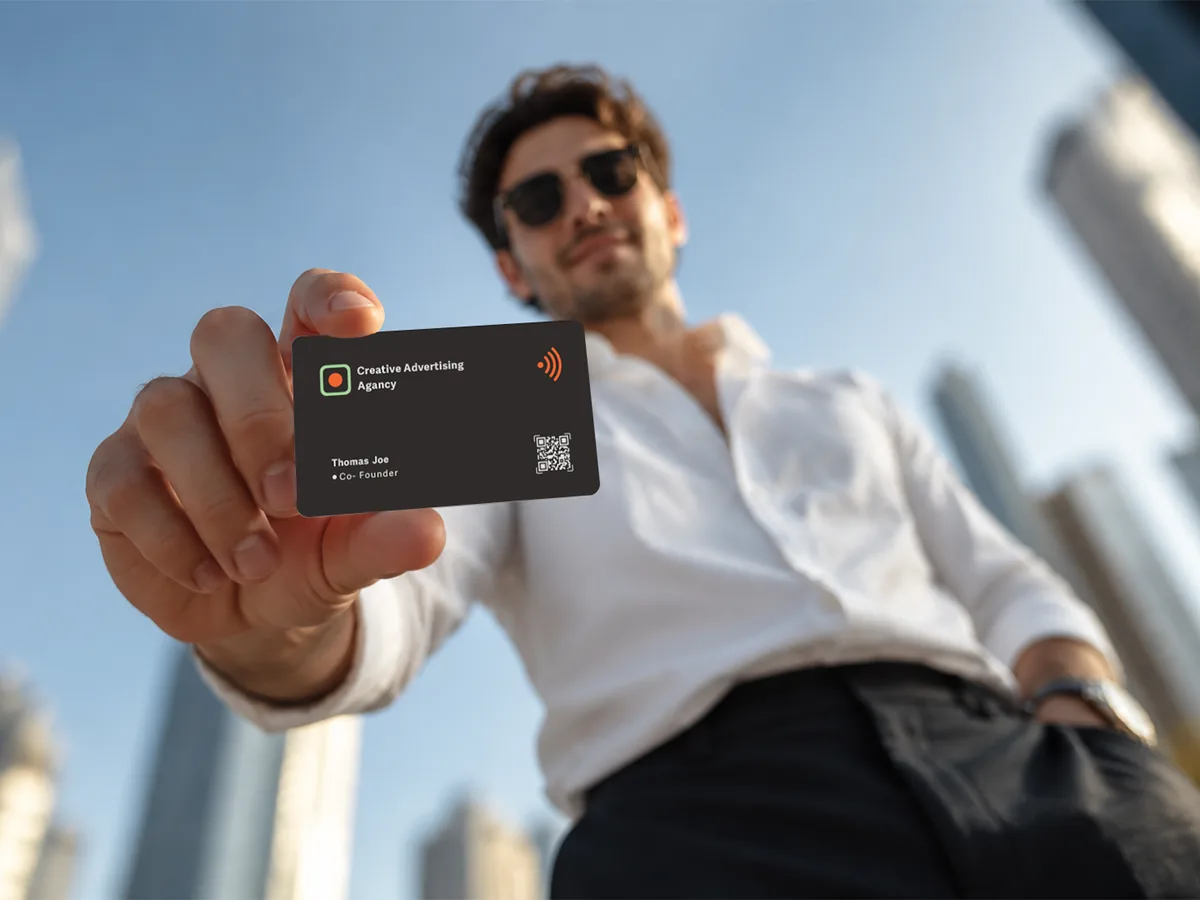 A man holding a custom NFC business card, with Dubai&rsquo;s towers behind him