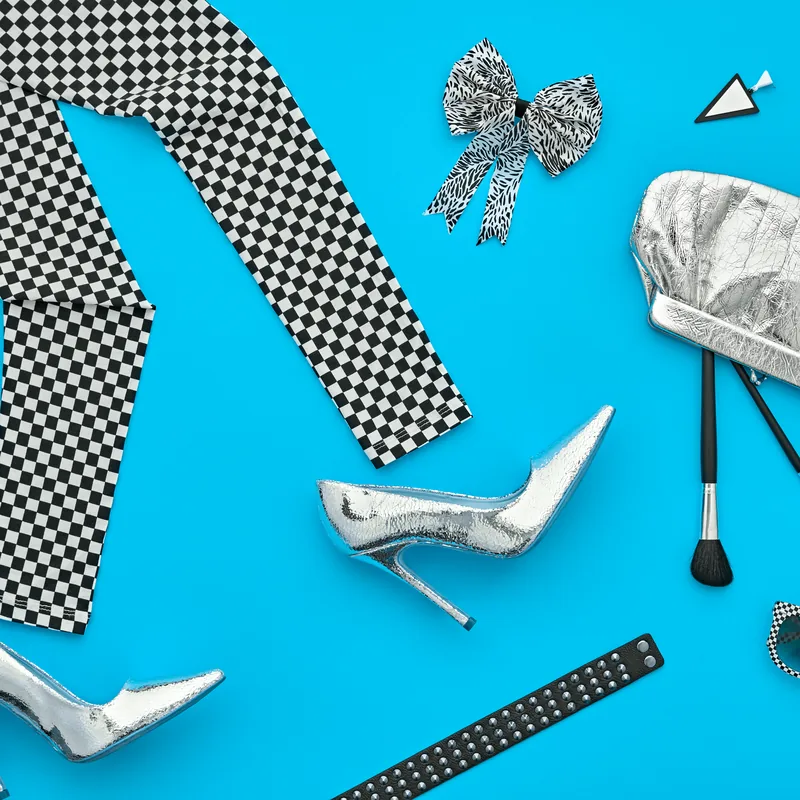 A fashion flat lay of heels, sunglasses, brushes and a clutch on electric blue